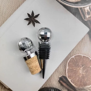 Disco ball wine stoppers with cork and metal bases on a white background with dried fruit