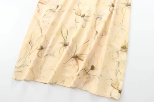 Gros plan d'une robe longue fleurie jaune clair montrant les coutures de l'ourlet