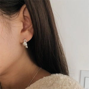 Detailed view of silver knot earrings worn by a model in minimalist Korean style