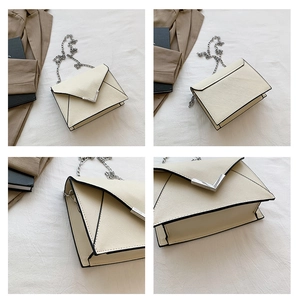 Detail view of cream white PU leather crossbody bag with metal V-buckle and chain strap