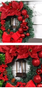 Detail of Christmas wreath with red poinsettia, pine cones, and a vintage candle lantern