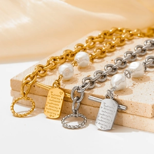 Close-up of gold and silver steel necklaces with baroque pearls and engraved soul mate tags