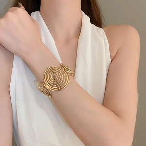 Detailed close-up of a golden wavy spiral cuff bracelet on a model's wrist