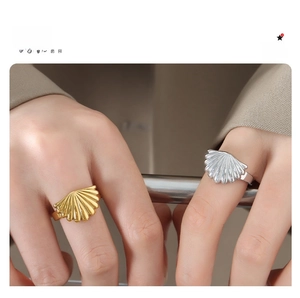 Detail of scalloped shell textured rings in gold and silver finish worn by a model