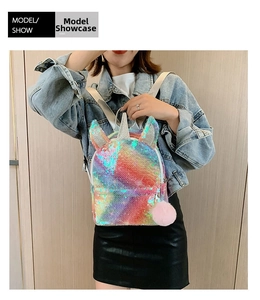 Girl wearing a shiny rainbow unicorn sequin backpack with a pink pompom charm