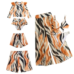 Flat lay of family swimwear set featuring orange and black tiger stripe patterns