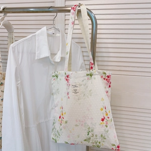 Detail of white cotton tote bag featuring floral ink patterns and a woven label detail