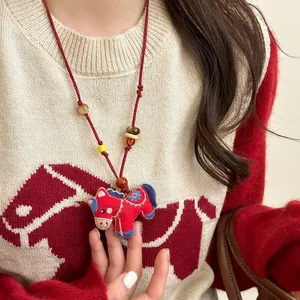 Ethnic style embroidered red pony pendant necklace with wooden beads on a knitted sweater