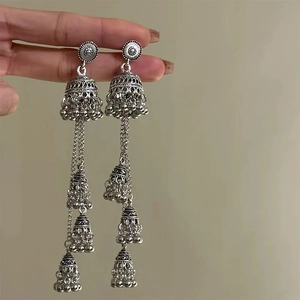 Detailed close-up of vintage silver Jhumka earrings with ornate bell tassels held by hand