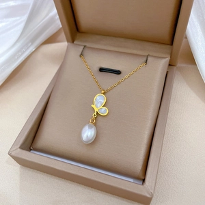 Golden butterfly necklace with mother of pearl and drop pearl in a beige jewelry box