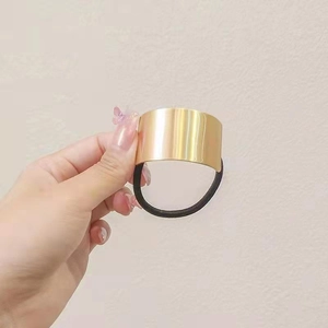 Detail of a minimalist golden metal hair cuff with a durable black elastic hair tie