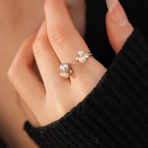 Detailed shot of an elegant pearl open ring featuring zircon on a black knit background