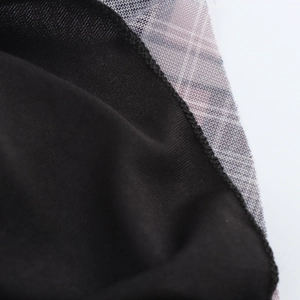 Gros plan des coutures entre le tissu noir et la maille à carreaux gris-violet