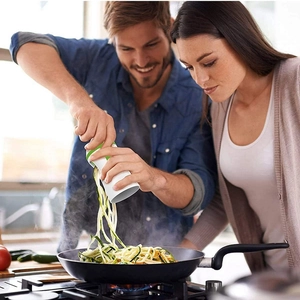 Un couple utilisant le coupe-légumes en spirale pour trancher des carottes en cuisine