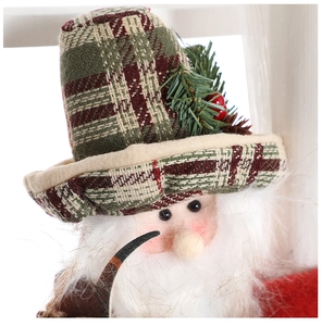 Close-up of plush Christmas doll with plaid hat, berries, and long white beard detail