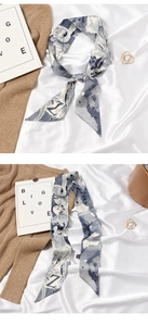 Detail of blue and white silk scarf tied elegantly on a soft beige knit fabric background
