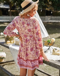 Dettaglio di un abito corto a fiori rosa con maniche lunghe, balze e scollo a V sul retro