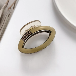 Detail of khaki oval hair claw clip with rhinestones and elegant matte finish texture
