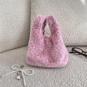 Détail du sac à main en fausse fourrure léopard rose avec pendentif nœud perlé élégant