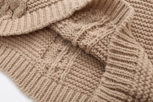 Close-up of khaki chunky knit sweater showing rib-knit cuffs and soft wool texture