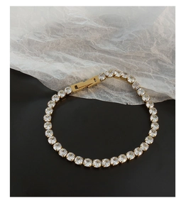 Macro view of 18K gold-plated tennis bracelet featuring sparkling zircon stones and claw settings