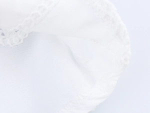 Vista macro di camicia in cotone bianco con ricami delicati e pizzo francese