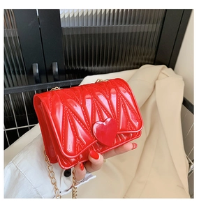Detail of red quilted jelly crossbody bag with heart clasp and gold chain strap