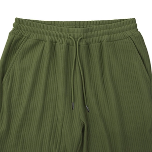 Detail of army green ribbed knit trousers featuring an elastic drawstring waistband