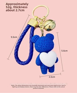 Blue resin bear keychain with white heart, gold bell and woven leather strap detail