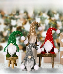 Detail von vier bunten gestrickten Weihnachtswichteln mit langen Mützen und Bommeln