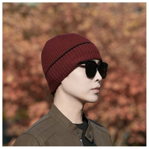 Detail view of burgundy knitted beanie showing vertical texture and black stripe accent
