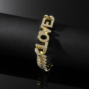 Close-up of gold Cuban link bracelet with LOVE pendant and sparkling white rhinestones