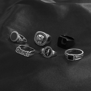 Macro detail of six-piece gothic ring set with skull and black stone on black silk