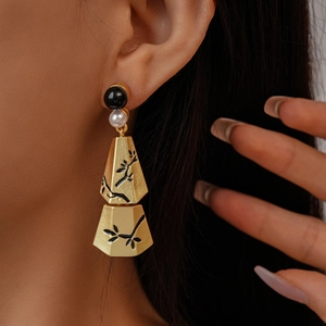 Close-up of vintage gold tassel earrings with pearl and black bamboo leaf pattern
