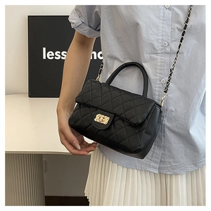 Detail of black quilted leather handbag with gold chain strap and turn-lock closure