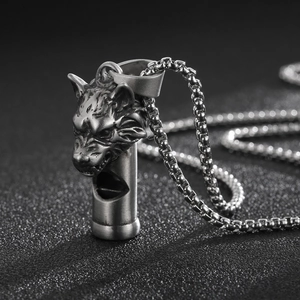 Détail macro du pendentif sifflet tête de loup argenté vintage avec chaîne gourmette