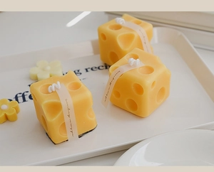 Detailed view of cheese-shaped yellow scented candles on a white decorative tray
