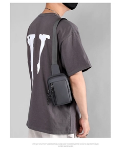 Rear view of a model wearing the minimalist dark grey water-resistant men's crossbody chest bag