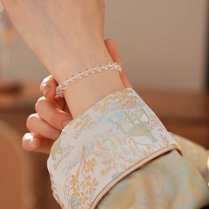 Close-up of a faceted clear crystal beaded bracelet worn with an embroidered sleeve