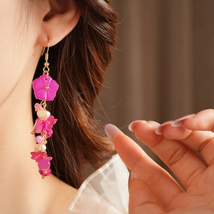 Détail de boucles d'oreilles fleurs roses à pompons perles portées par un mannequin