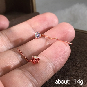 Dettaglio degli orecchini pendenti in oro rosa con ciondolo in zircone tenuti in mano