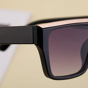 Close-up of black square sunglasses with rose gold metal trim and purple gradient lens