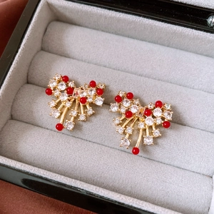 Detail von 14k vergoldeten Schleifenohrringen mit weißen Zirkonia und roten Perlen