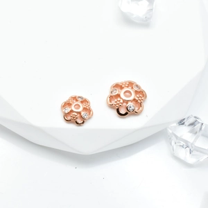 Rose gold flower bead caps with micro-pave cubic zirconia on white geometric platform