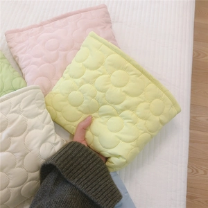 Detailed close-up of quilted floral texture on soft padded nylon pouches in pastel colors