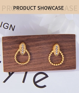 Macro detail of gold plated twisted hoop earrings with white rhinestone accents