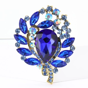 Detail shot of pear-shaped blue crystal brooch with rhinestones on gold metal base