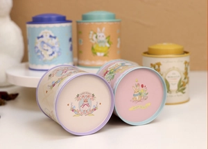 Detail of round tin cans showing rabbit illustrations and Happy Bunny printed on bottom