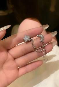 Detailed close-up of an elegant silver star and crescent moon tassel ear cuff earring set.