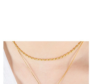 Detail of layered gold beaded chain necklace worn on model neck for elegant look